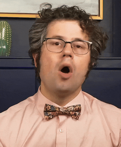 GIF of Zachary Rubin talking into the camera. He wears a salmon colored shirt, with a floral bow-tie.