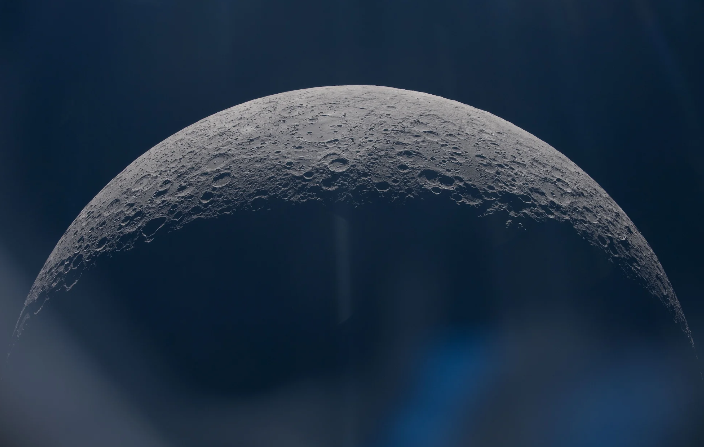 An image of half of the moon, with image artifacts caused by the window of the Orion capsule.