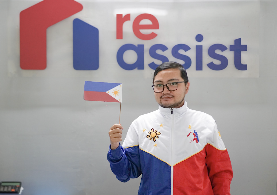 Team standing in front of the REassist sign with the Philippine flag