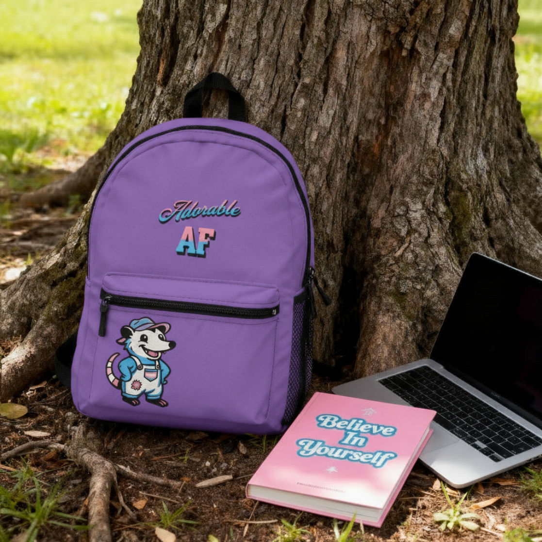 Purple backpack with "Adorable AF" on the top half and a cartoon opossum wearing transgender pride overalls on the bottom pocket Purple backpack with "Adorable AF" on the top half and a cartoon opossum wearing transgender pride overalls on the bottom pocket