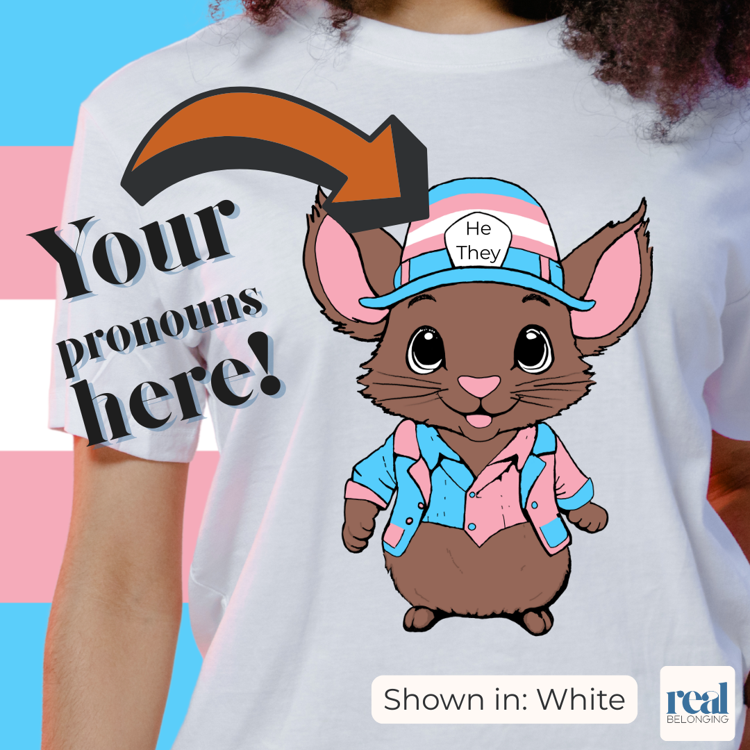 Transgender flag background with model wearing white shirt showing hand-drawn brown mouse wearing transgender colors on jacket and hat, with "Your pronouns here" pointing to the hat where buyers can customize the shirt with their own pronouns on the mouse's hat Transgender flag background with model wearing white shirt showing hand-drawn brown mouse wearing transgender colors on jacket and hat, with "Your pronouns here" pointing to the hat where buyers can customize the shirt with their own pronouns on the mouse's hat