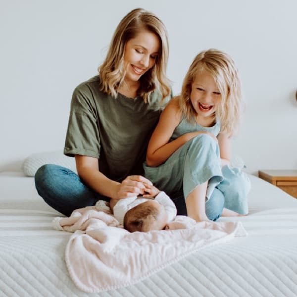 Woman sits with her two young children on Leesa mattress