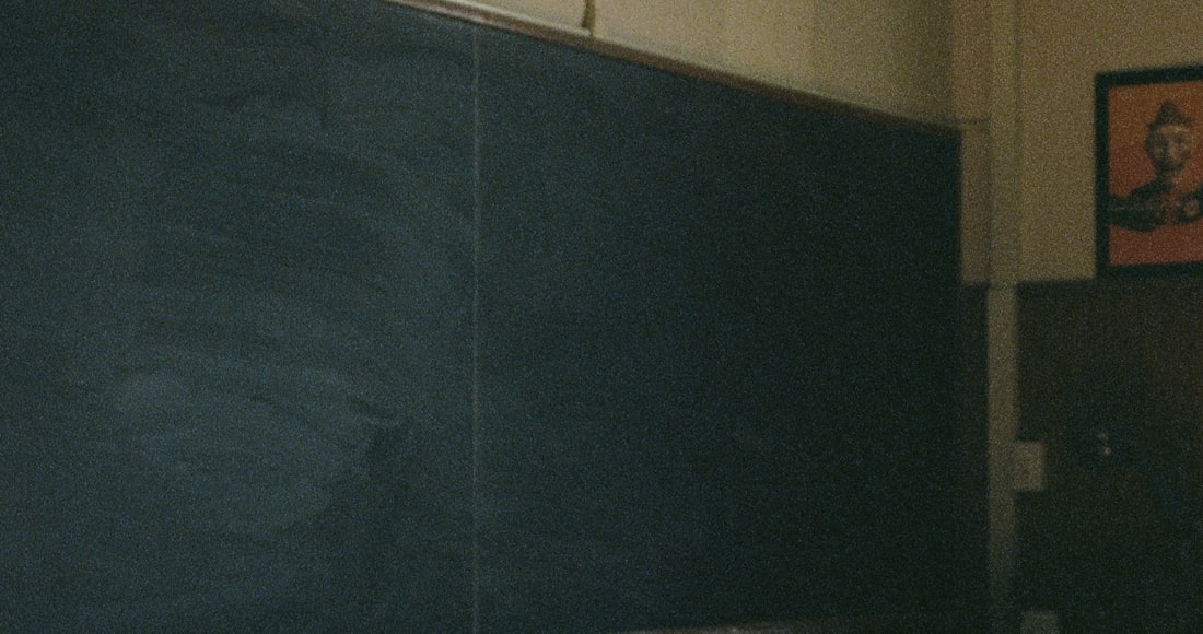 An empty vintage classroom with wooden desks and a blackboard