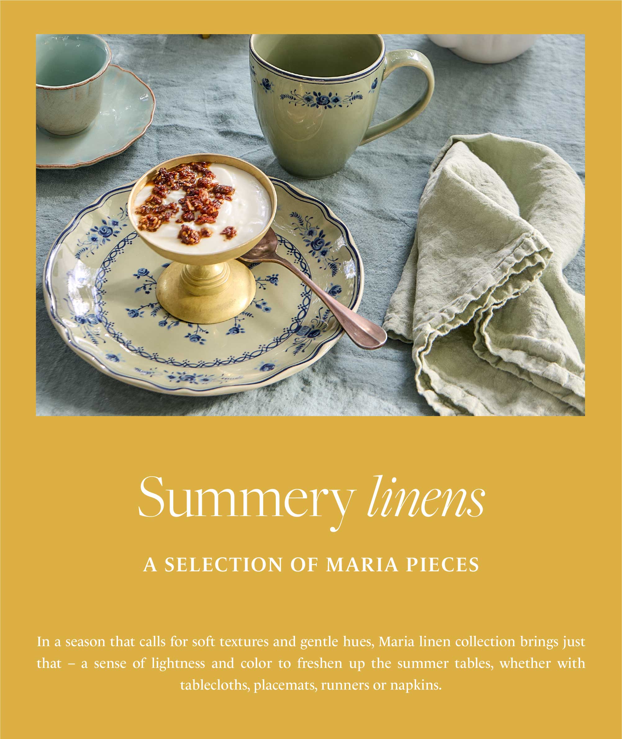 Summery linens, a selection of Maria pieces. Creamy dessert with granola in a small footed dish, on a plate with a blue floral pattern, next to a cup and mug with the same blue floral pattern, and a light green linen napkin on a blue-grey tablecloth. Text below describes the Maria linen collection