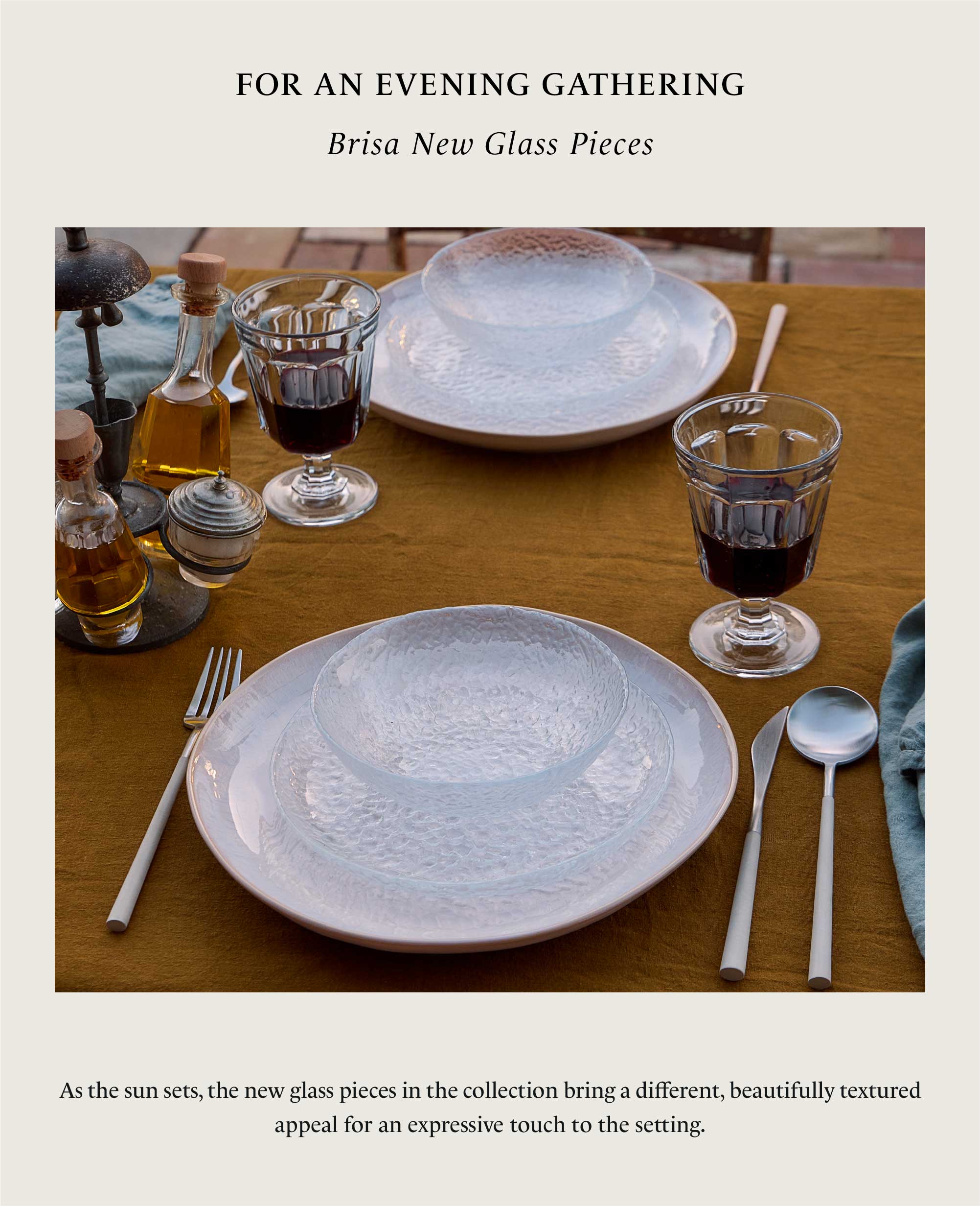 Table set at sunset with new glass pieces from the Brisa collection, textured glass plates and bowls, red wine glasses and white cutlery on a mustard tablecloth, with text For an evening gathering and description of the glass pieces bringing a textured appeal for an expressive touch