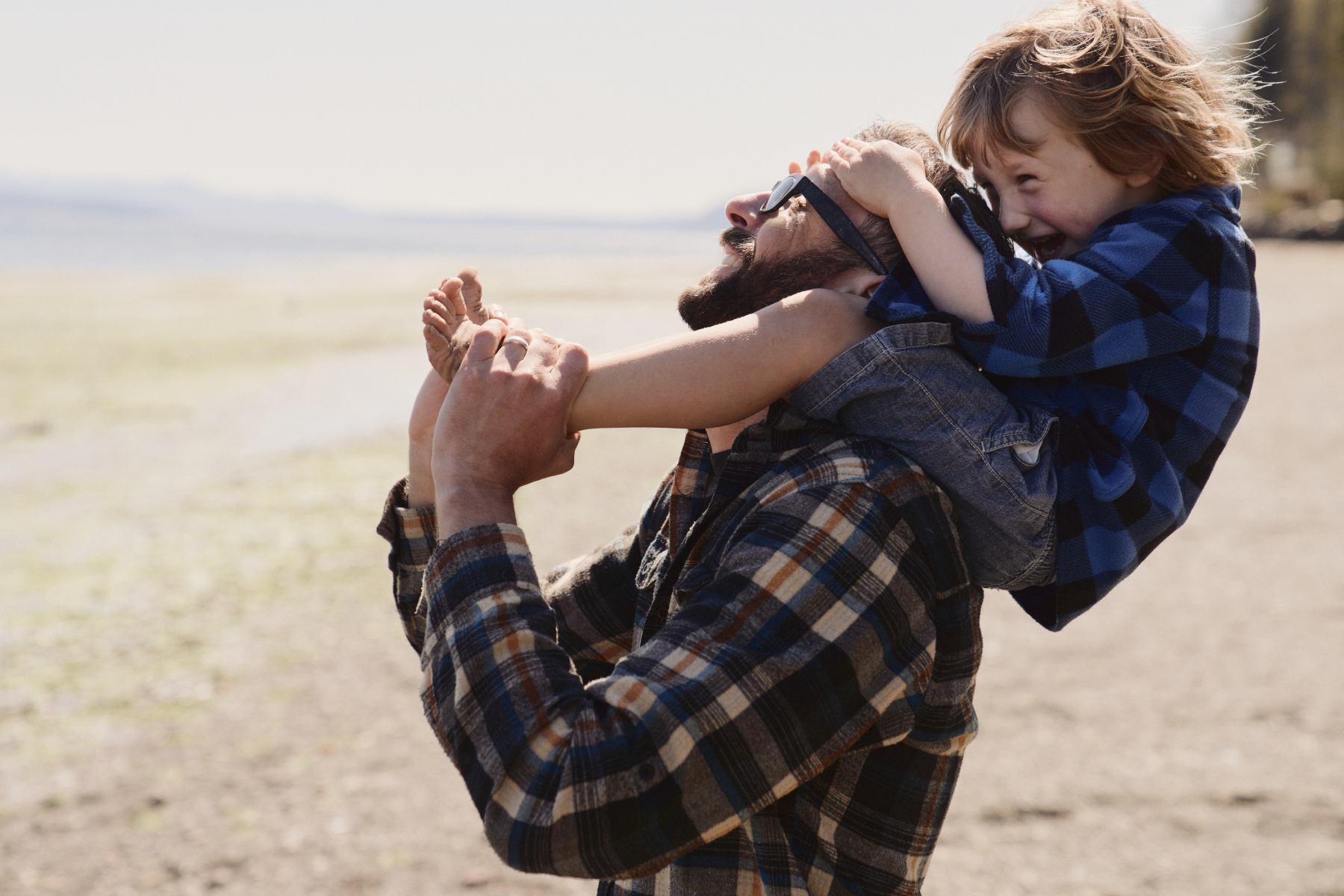 Father carrying his son on his shoulders outdoors, sharing a moment together.