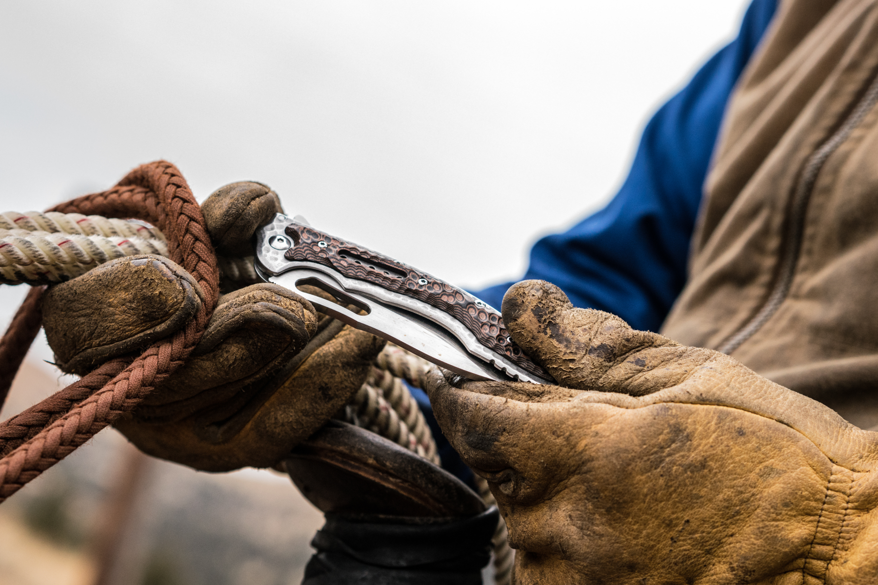 CRKT folding knife cutting rope during ranch work.