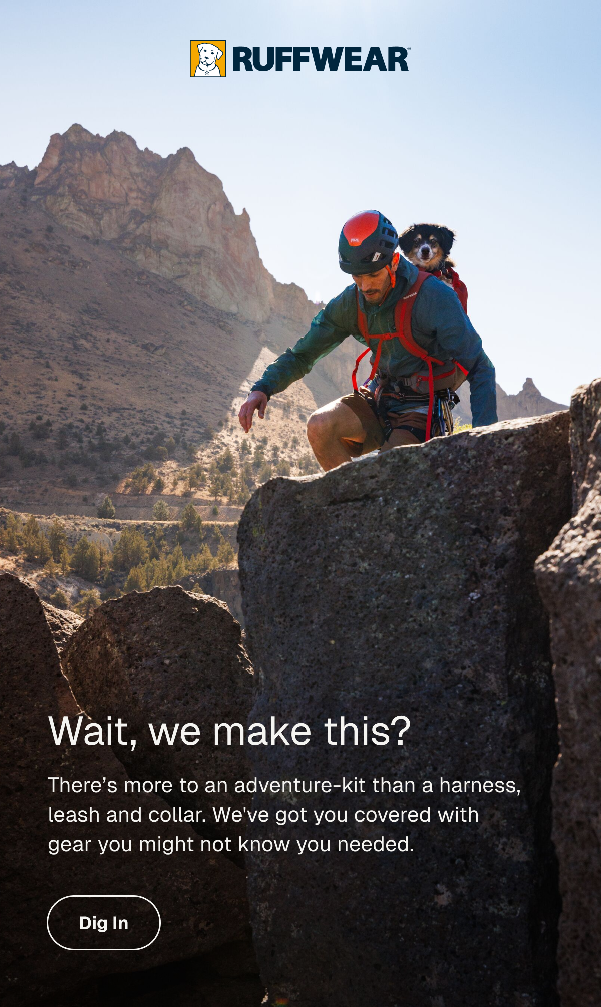 A male climber and dog in backpack scramble over rocks