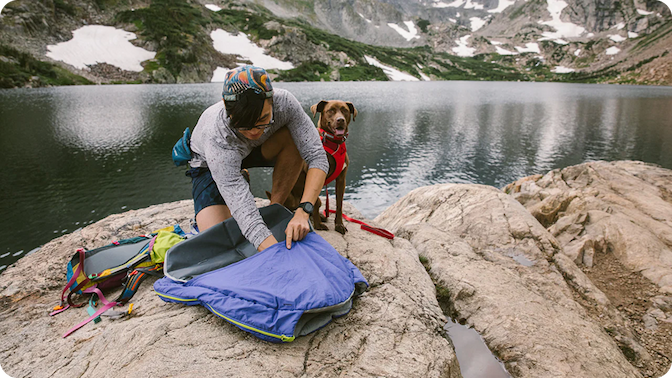 A human adds the Highlands™ Sleeping Pad to the Sleeping Bag