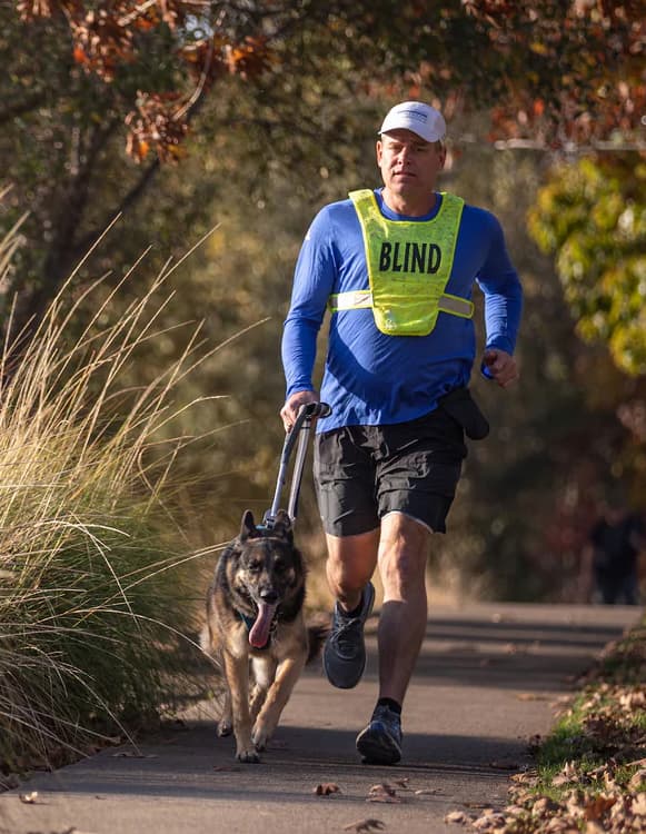 A human and guide dog duo run together.