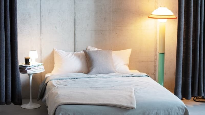 Grey cashmere cushion and bedspread styled with light bedding in a contemporary bedroom