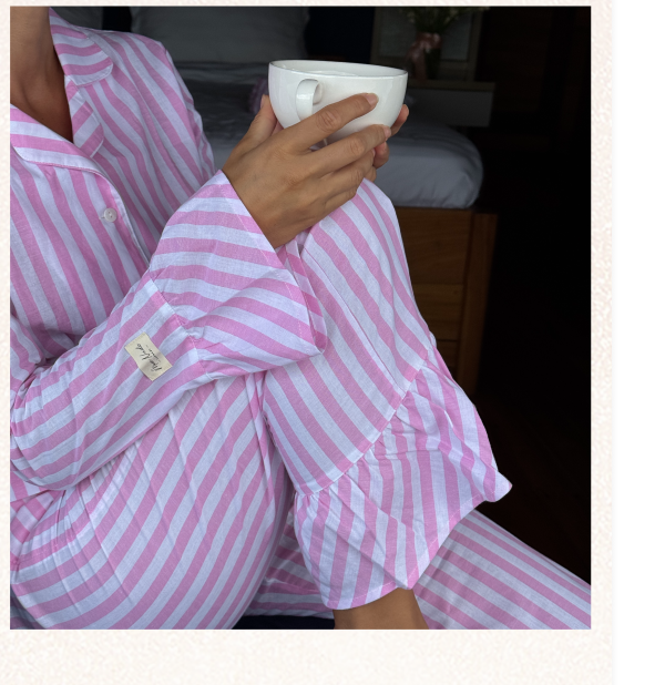 Woman in pink striped pajamas holding a cup.