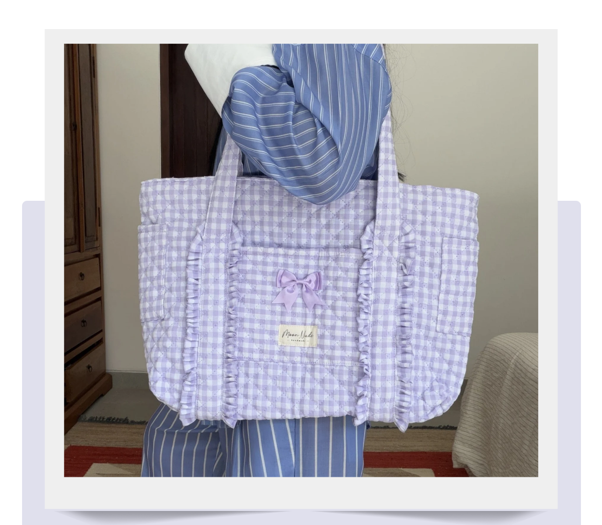 A person holding a lavender checkered tote bag