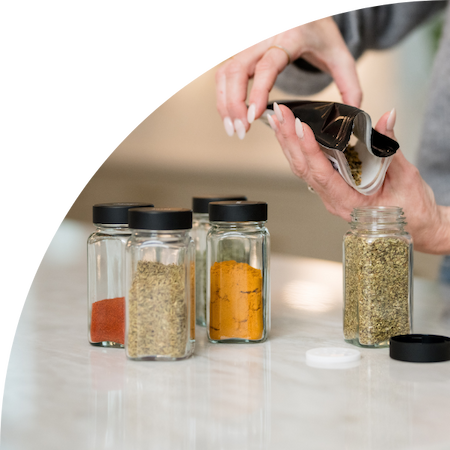 A person decanting spices into spice jars