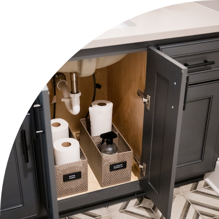 Perforated baskets holding cleaning supplies under the sink