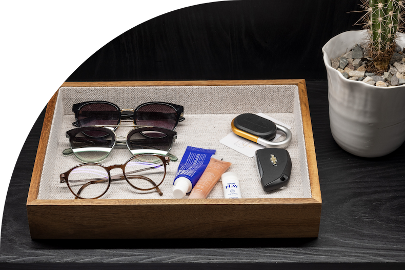 Sunglasses, lip gloss, and keys organized in a lined acacia tray