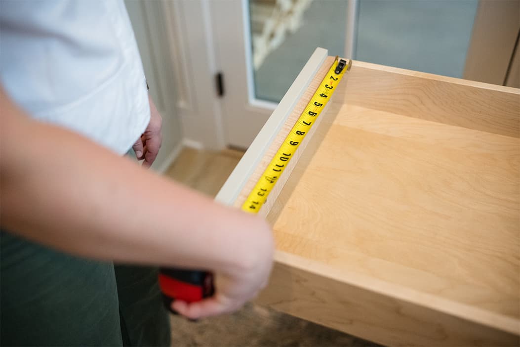 A person measuring the width of a drawer