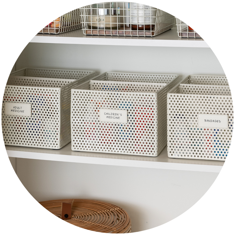 Labeled perforated baskets on a bathroom shelf