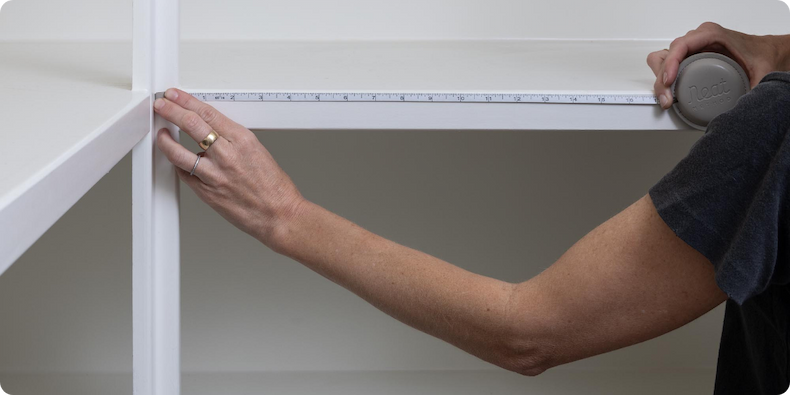 A person measuring the length of a shelf.