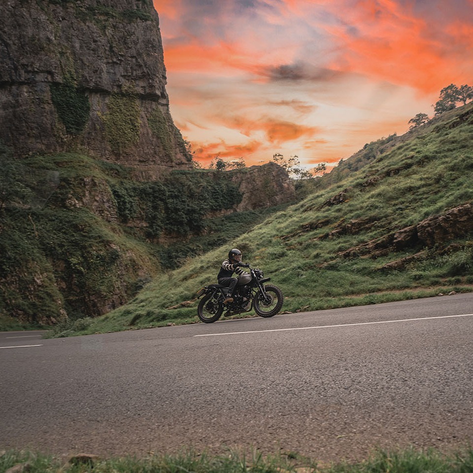 A 250cc Titanium Grey MM Mushman makes its way round one of Cheddar Gorge's many turns with a coral sunset in the background