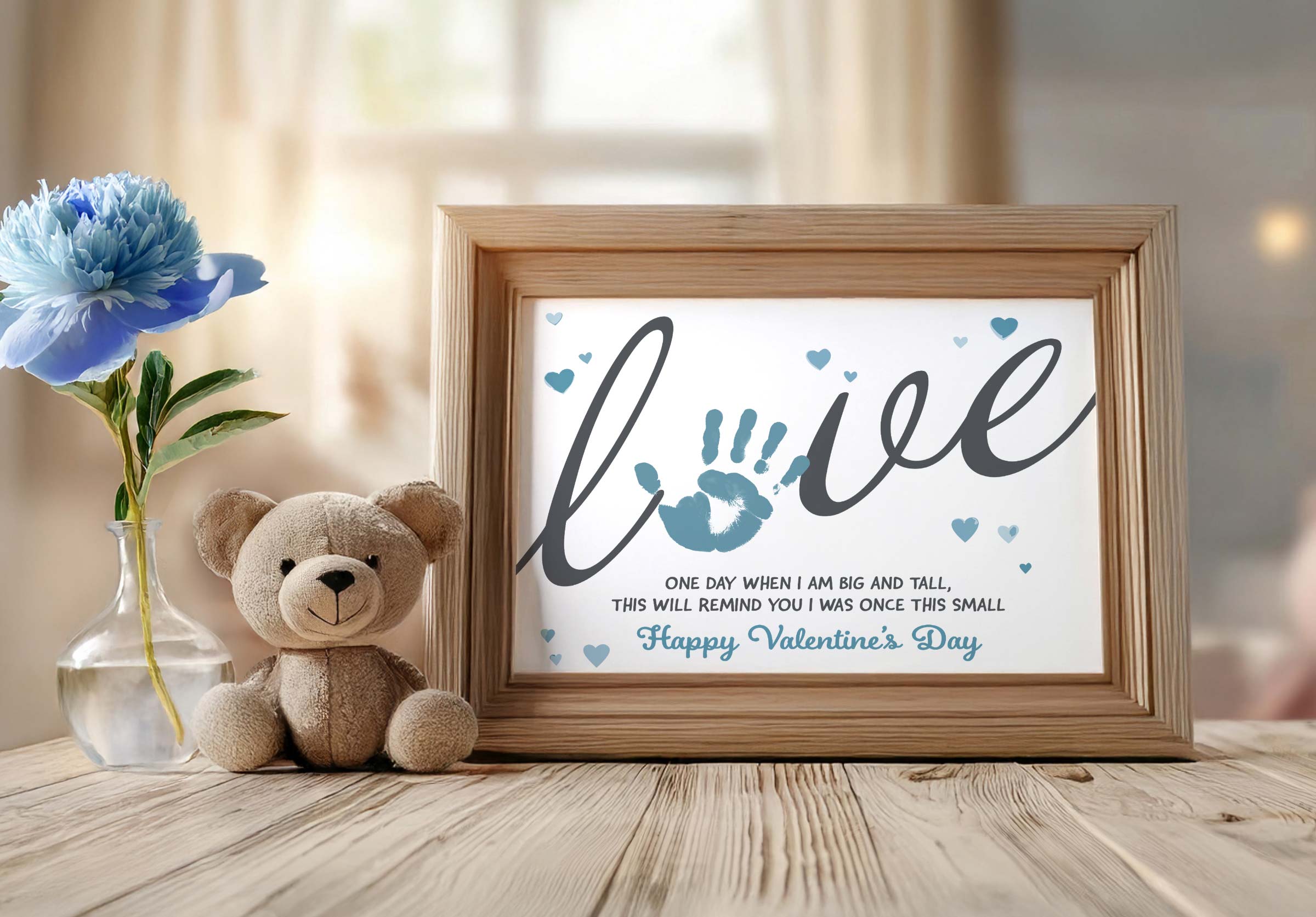 Valentines handprint craft in frame next to teddybear and blue flower