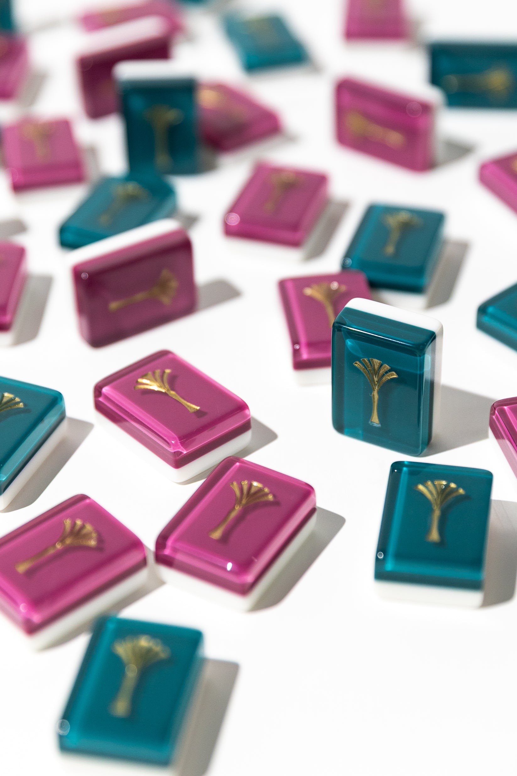 Jewel-toned mahjong tiles in magenta and teal with gold engraving