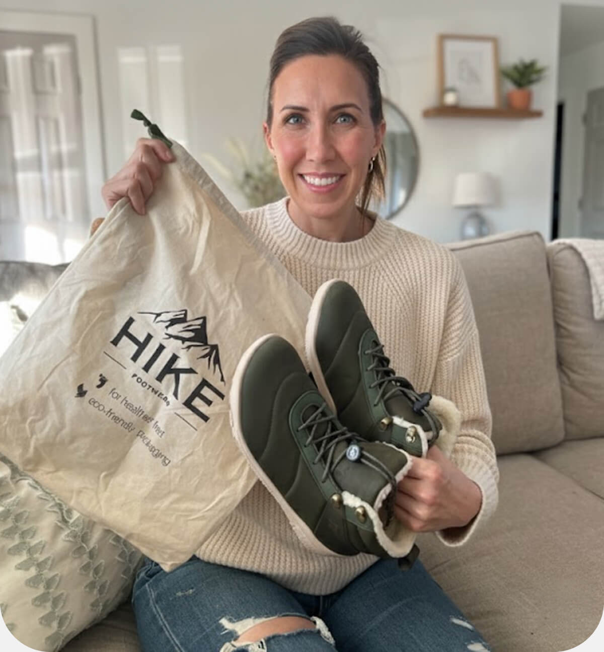 Wendy sitting on the sofa holding HF barefoot shoes