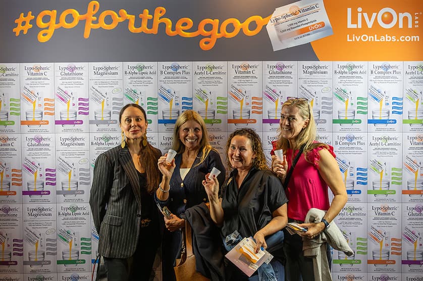 4 women standing in front of a livon labs step and repeat with shot glasses