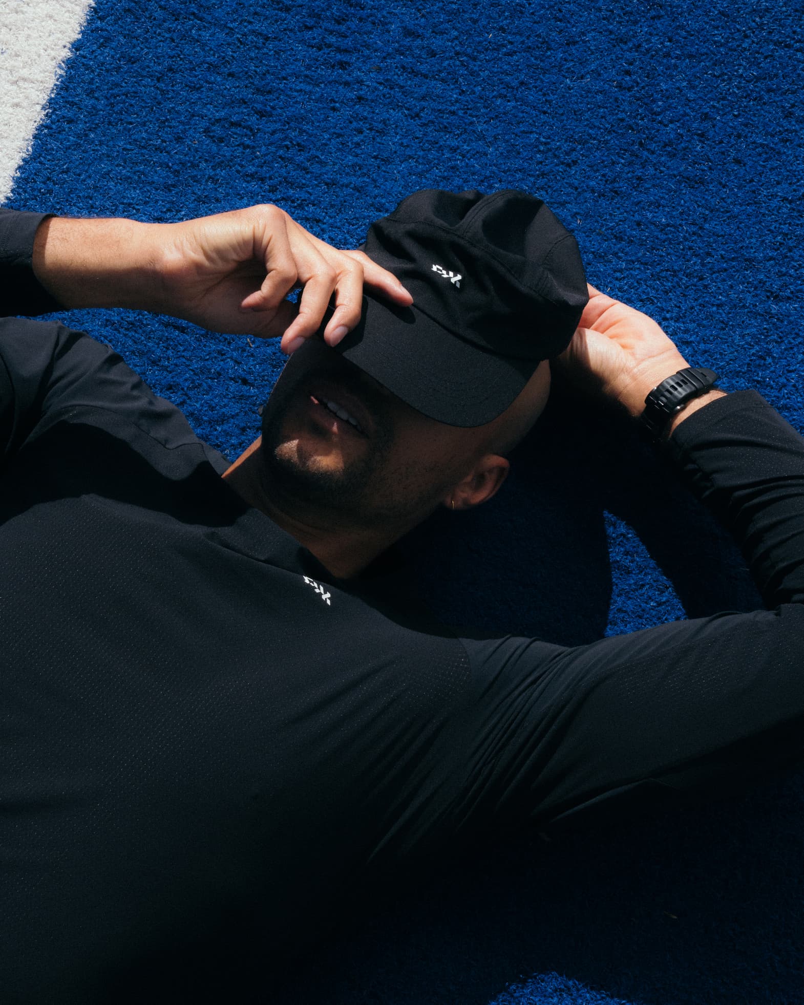 Man wearing the black Pedal Mafia Pro Technical Hat while relaxing trackside.