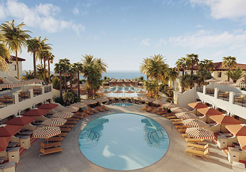 Outdoor pool surrounded by lounge chairs and umbrellas