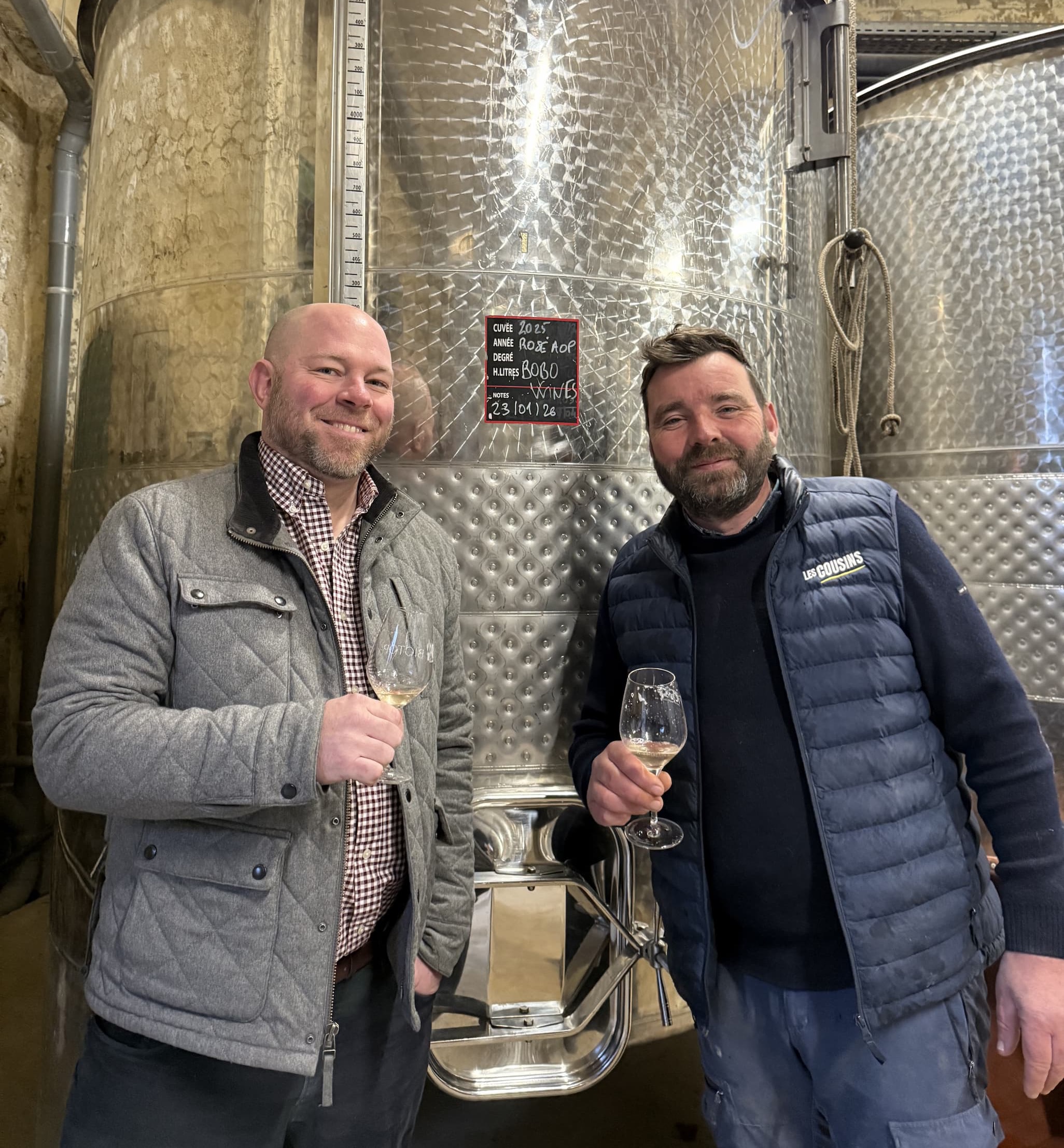 an image of two men standing next to each other holding wine glasses