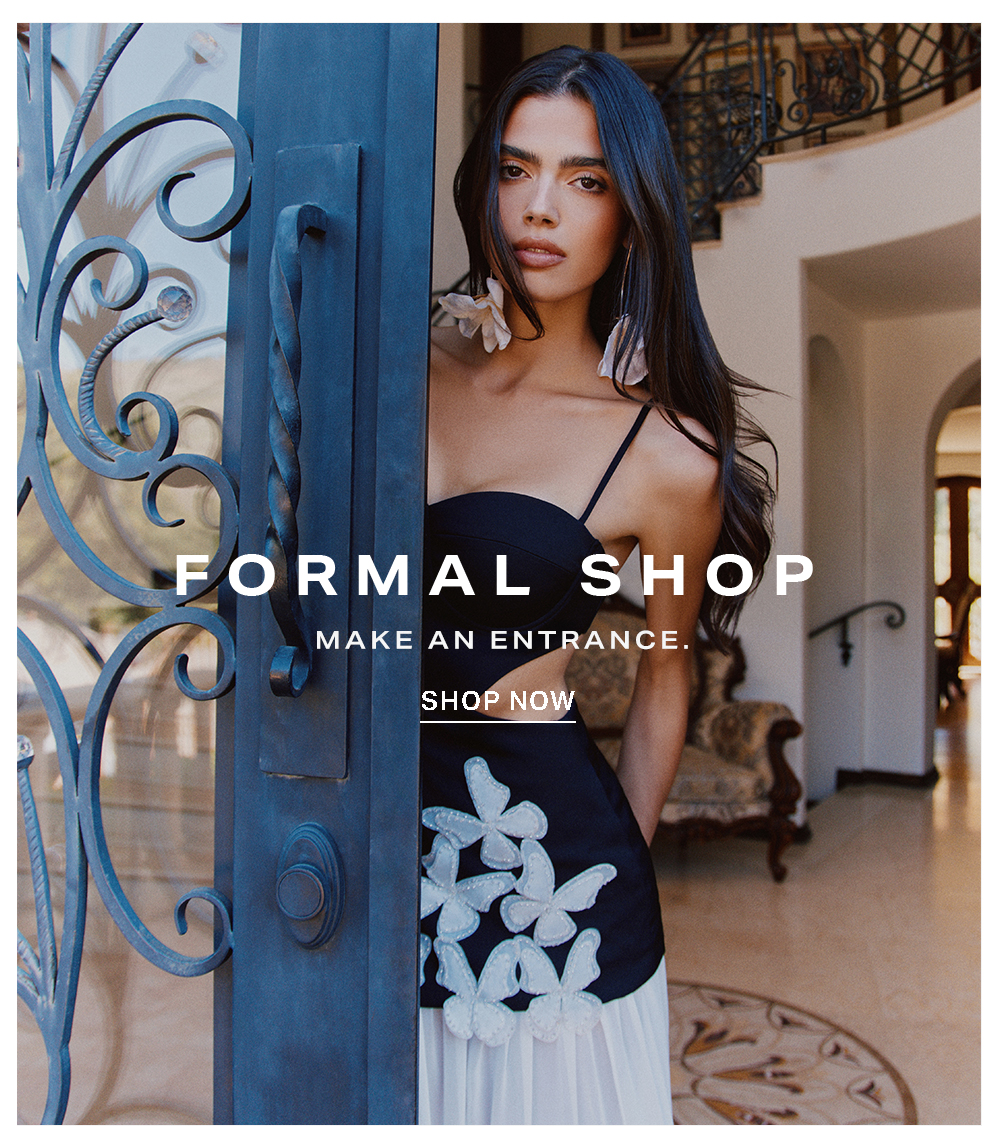 Elegant woman in black and white formal dress with butterfly details, peeking through an ornate door. Shop sophisticated formal wear for special occasions.