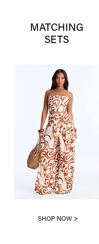 Woman wears a stylish beige & brown tribal print matching set: strapless crop top & wide-leg pants, with a woven bag. Discover our matching sets.
