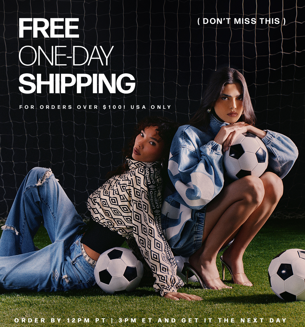 Free One-Day Shipping on Umbro fashion & sportswear orders over $100 (USA). Two women pose with soccer balls on a field.