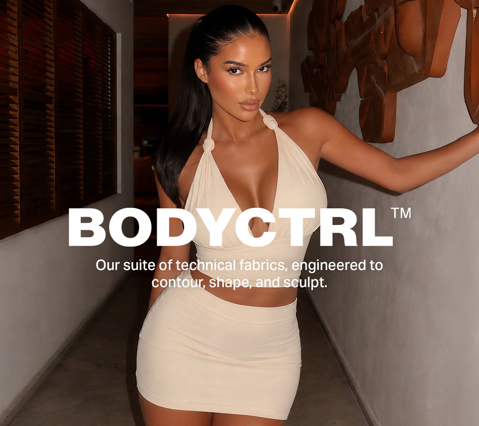Confident woman in a light beige BODYCTRL contouring halter top and mini skirt. Highlights technical fabrics for sculpting shapewear.