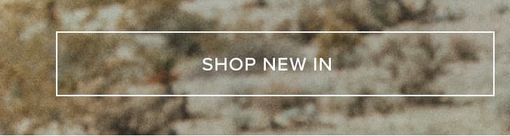 White "SHOP NEW IN" button on a blurry mottled background of earthy brown and green tones. Discover our latest collection and new arrivals.