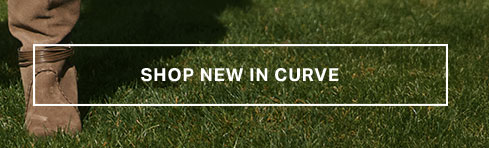 Tan suede boot with wrapped ankle detail on green grass. Text: SHOP NEW IN CURVE. Promotes new arrivals in the Curve collection.