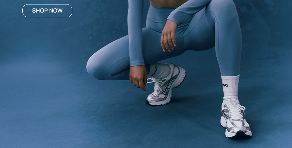 Shop the new collection featuring a matching blue activewear set and silver athletic sneakers, showcased against a textured blue background.