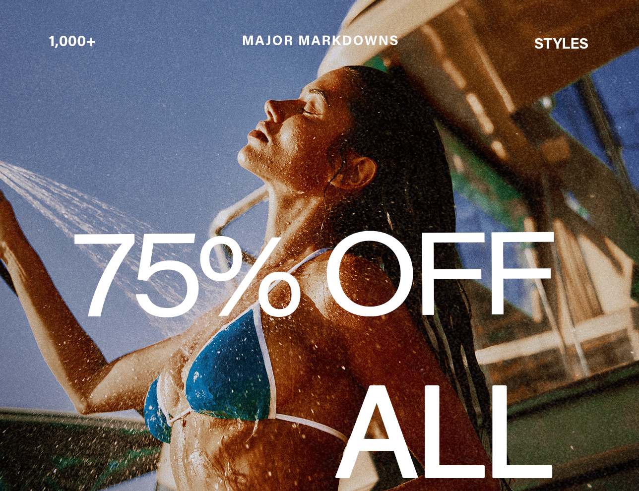 Woman in blue bikini showering, face tilted towards water. Text: 75% OFF ALL major markdowns on 1000+ styles. Shop all sale.