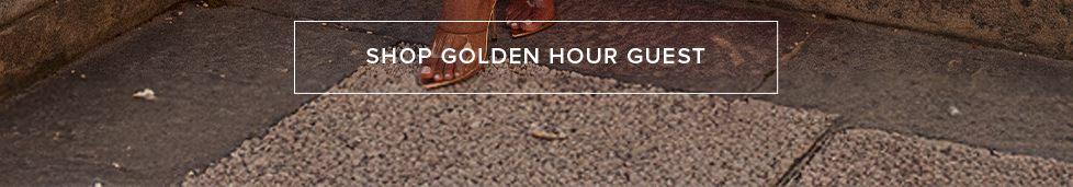 Elegant gold strappy heels on a textured stone path, banner promoting a link to shop the Golden Hour Guest wedding guest collection.