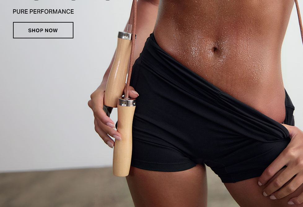 Sweaty athlete holds wooden jump rope, wearing black athletic shorts for peak fitness performance.