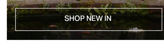 Green moss and ferns on a dark stone wall above reflective water. White "SHOP NEW IN" banner for exploring new arrivals and latest collection items.