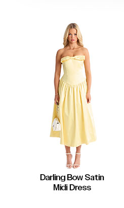 Model wears a bright yellow strapless Darling Bow satin midi dress with an A-line skirt. She holds a white bag; white heels complete the elegant look.