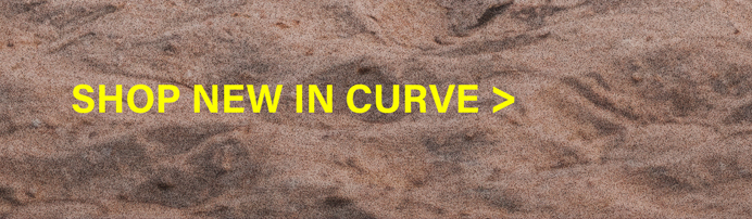 Yellow "SHOP NEW IN CURVE" text on a textured, light brown sandy background with subtle ripples. Discover new arrivals in curve fashion.