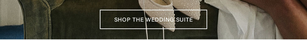 Elegant ivory bridal flats with textured dots, white dress, and green fabric. Shop the Wedding Suite for stylish wedding day essentials.