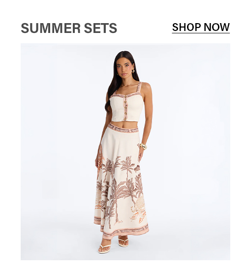 Elegant woman in a cream palm print two-piece summer set: crop top & maxi skirt. Shop women's tropical resort wear.