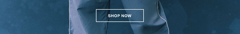 Close-up of stylish deep blue activewear, featuring white piping and comfortable fabric. A "SHOP NOW" button invites exploring our performance apparel.