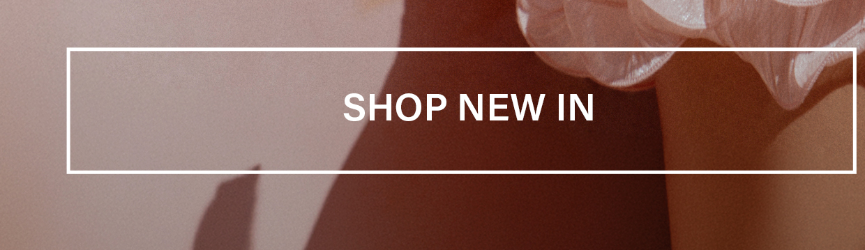 SHOP NEW IN banner over warm, sunny pink ruffled apparel and soft shadows, promoting the new arrivals boutique clothing collection.