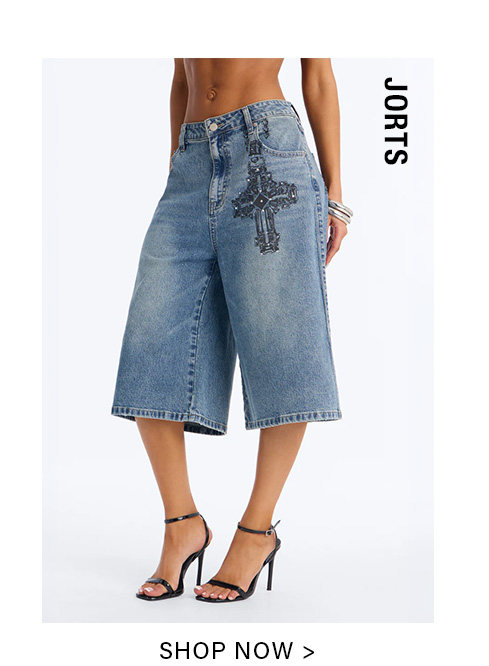 Mid-length light blue denim jorts featuring an elaborate black sequined cross on the thigh, worn with high heels. Shop the stylish jorts collection now.