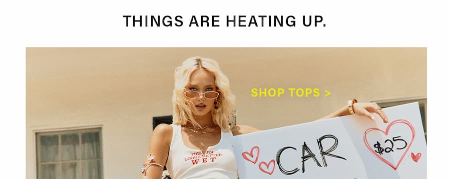 Blonde woman in sunglasses wearing 'WET' tank top, holding '$25' sign. Shop trendy summer tops & new arrivals!